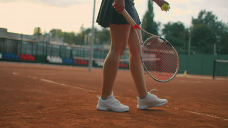 Slow-motion-of-woman-making-tennis-serve.-Slow-motion:-section-of-woman-bouncing-ball-on-tennis-court.-athlete-serves-the-tennis-ball.-Young-woman-is-hitting-the-ball-with-her-tennis-racket-at-sunset